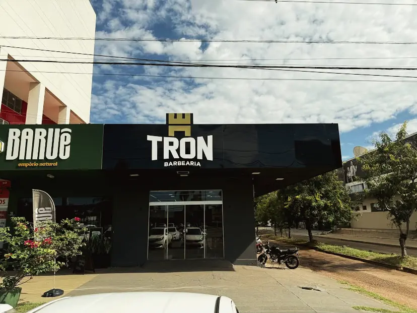 Fachada da TRON Barbearia durante o dia, com o letreiro sobre painel escuro